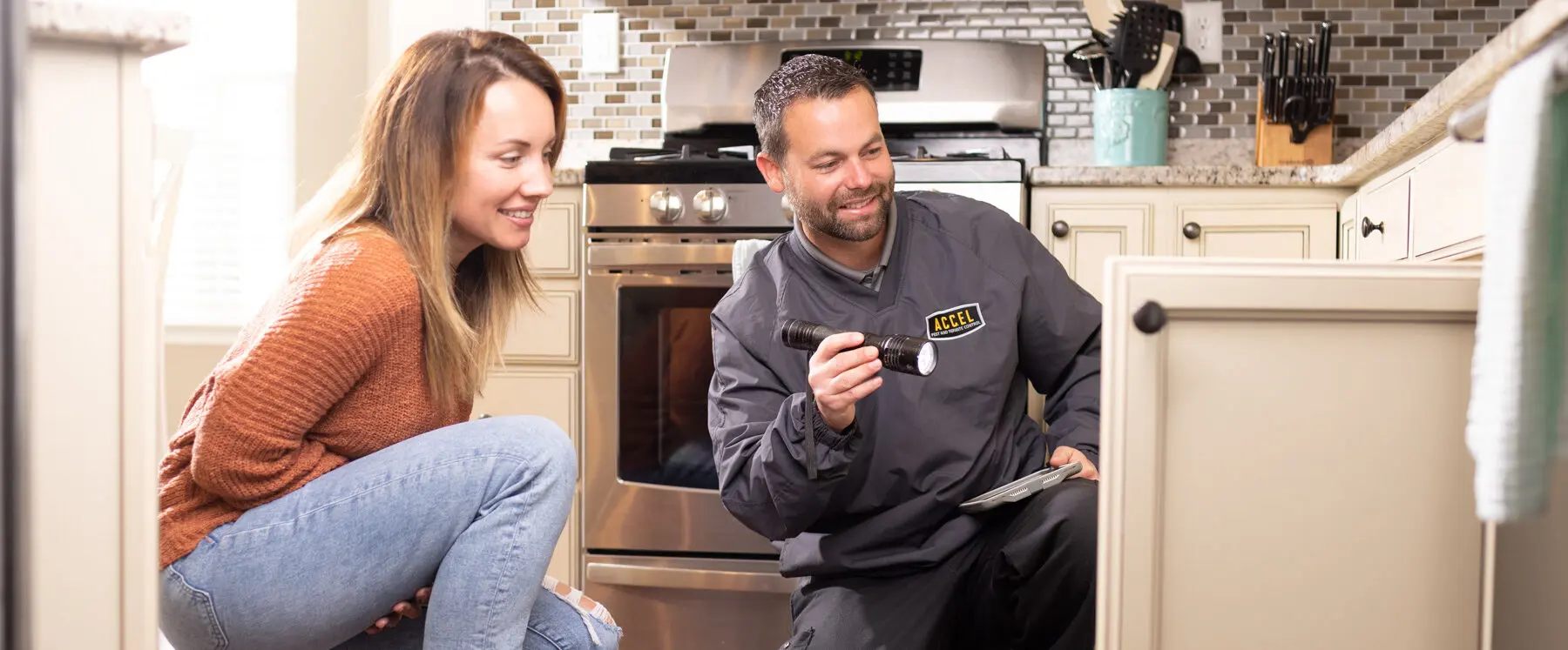An exterminator works alongside a woman in her home looking for signs of an infestation.
